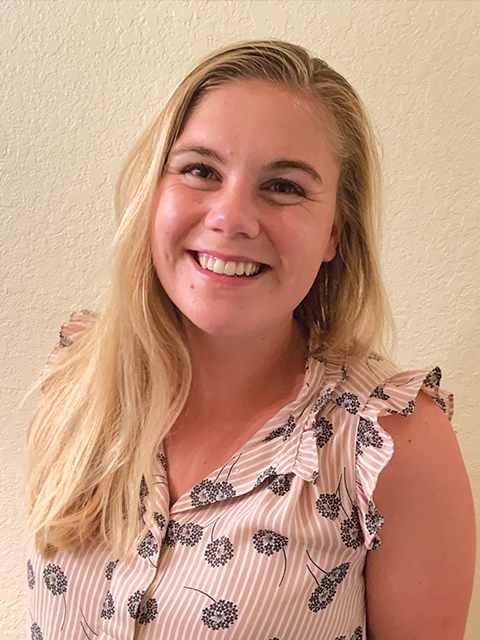 A man wearing glasses is sitting in front of a laptop computer.