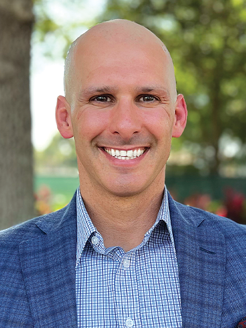 A man in a suit and white shirt is smiling for the camera.