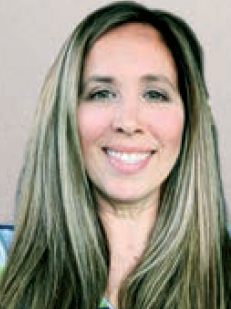 A woman wearing glasses and a white shirt is smiling for the camera.