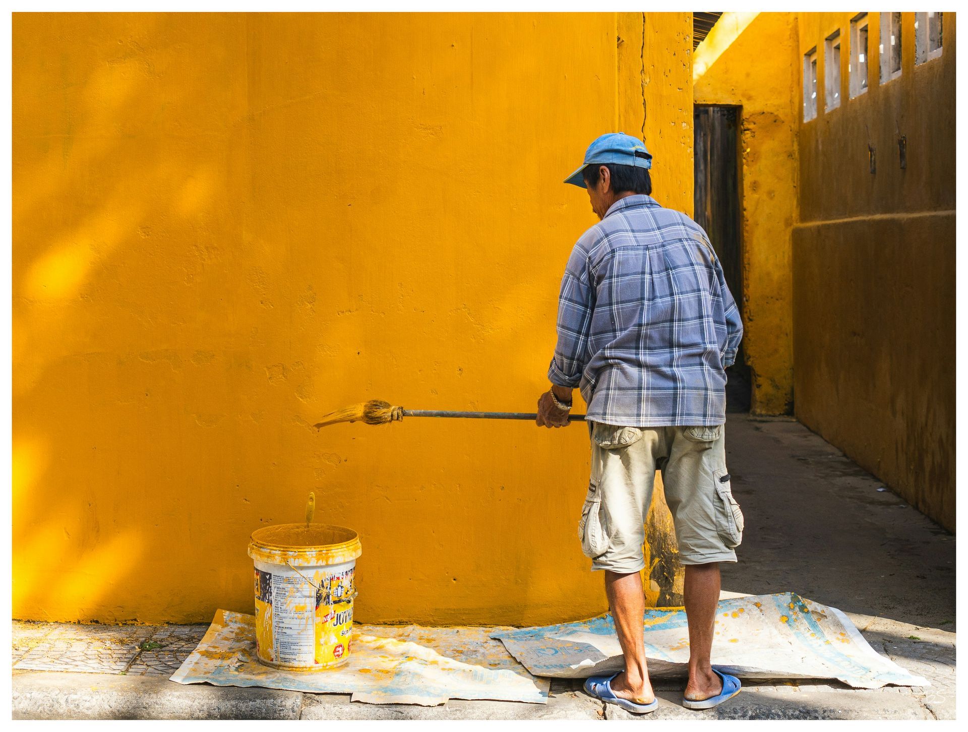 tanned man painting wall orange yellow