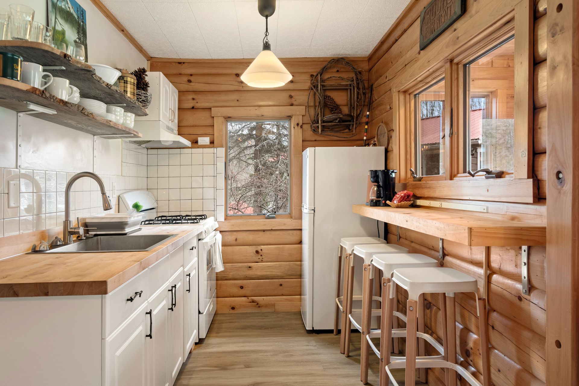 Indoor photo of the Belleayre Lodge's Cabin 5A, hotel-style kitchenette, with bar stools, refrigerator, sink, and stove.
