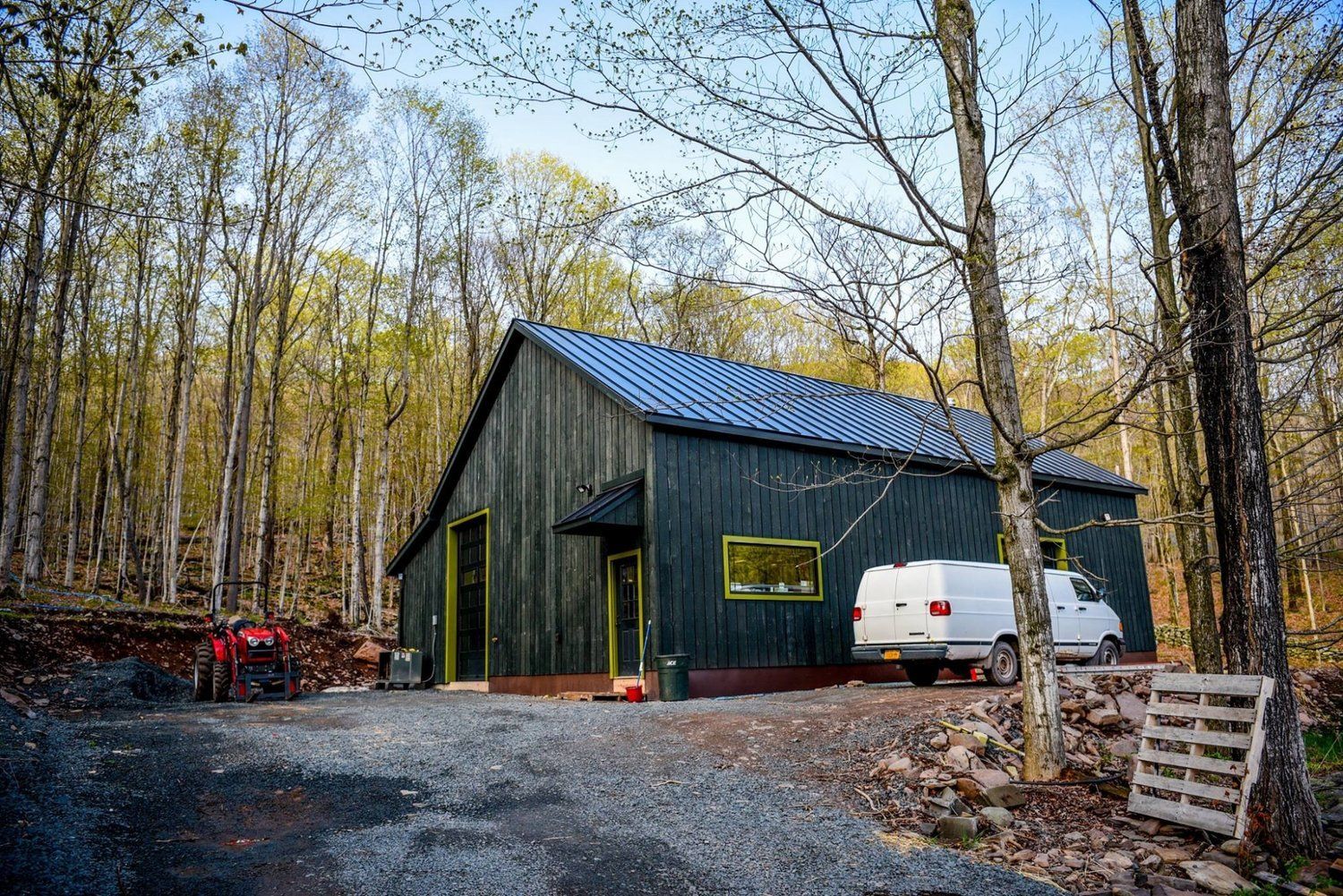 Exterior of a wooden building in the woods with a white van.