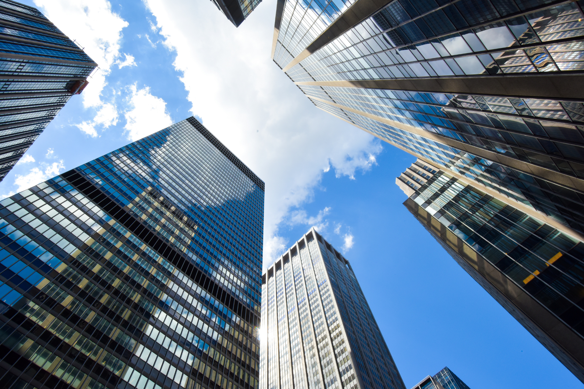 Looking up at a group of tall buildings with a blue sky in the background