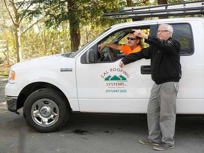 Two men by white work truck, one pointing. Truck has 