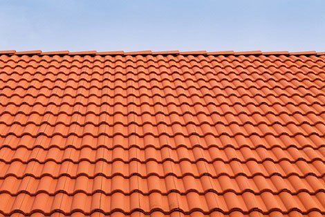Red ceramic tile roof against a clear blue sky.
