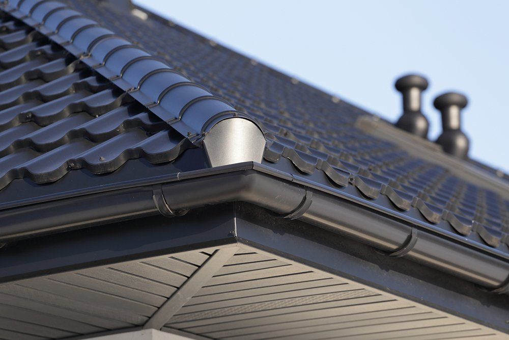 Black metal roof with gutters, a corner, and two black chimney vents.