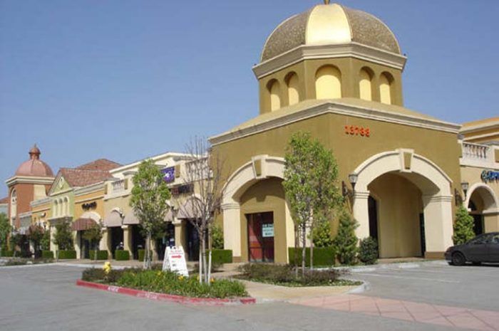 Exterior of retail and outdoor mall area with multi-colored stucco sides. A corner retail store area has a golden dome on top.