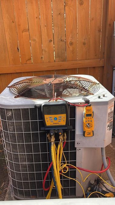 Outdoor HVAC unit with exposed wiring, yellow test equipment, and fan visible against a wooden fence