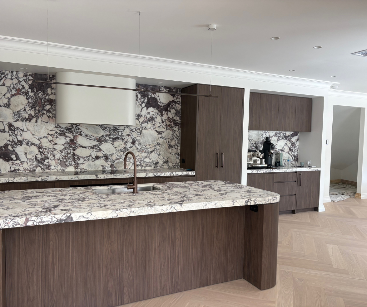 Modern kitchen with dark wood cabinets, marble island, and patterned backsplash, viewed in an open room Modern kitchen with dark wood cabinets, marble island, and patterned backsplash, viewed in an open room