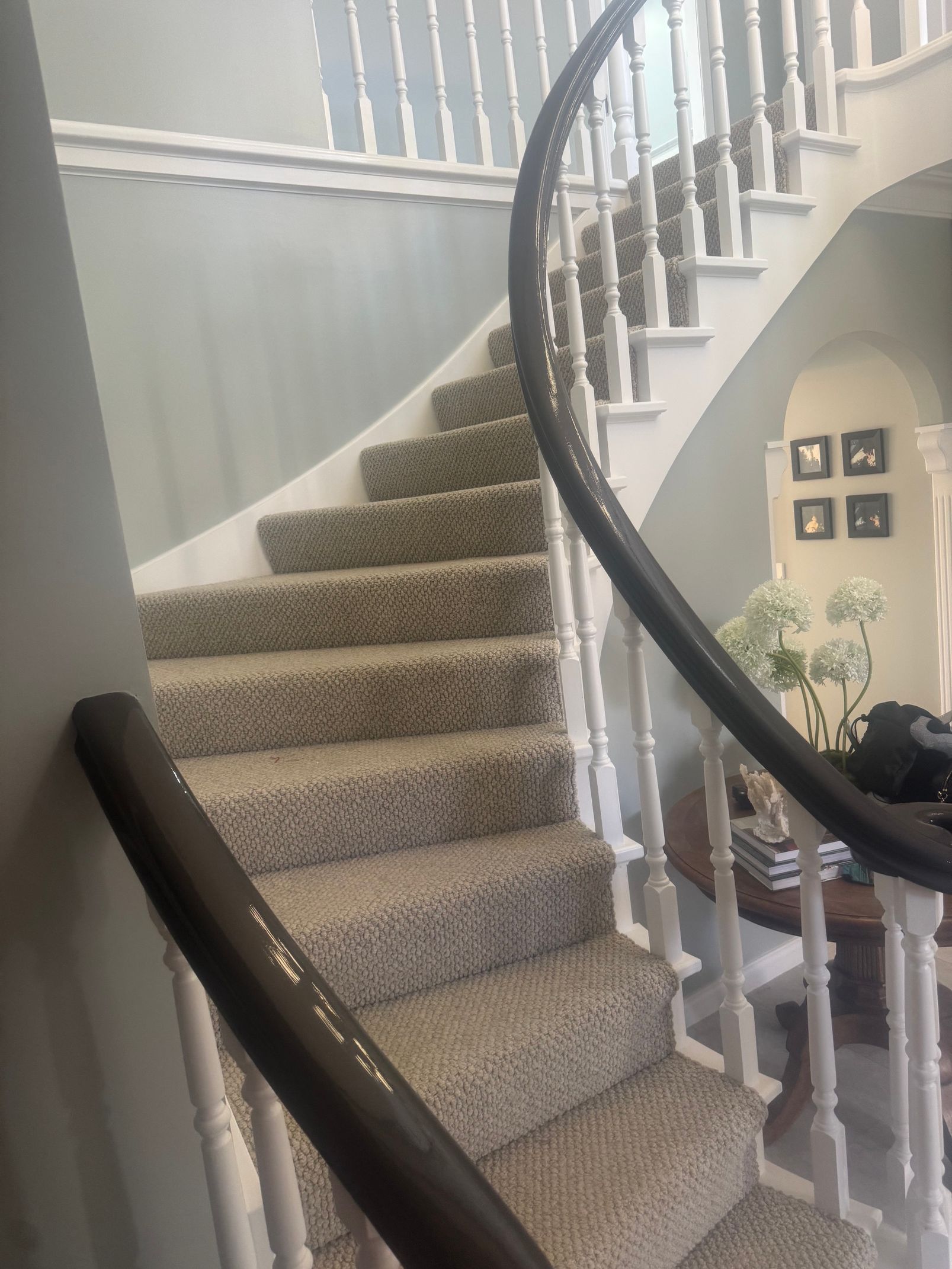 Curved carpeted staircase with white banister in a bright home interior