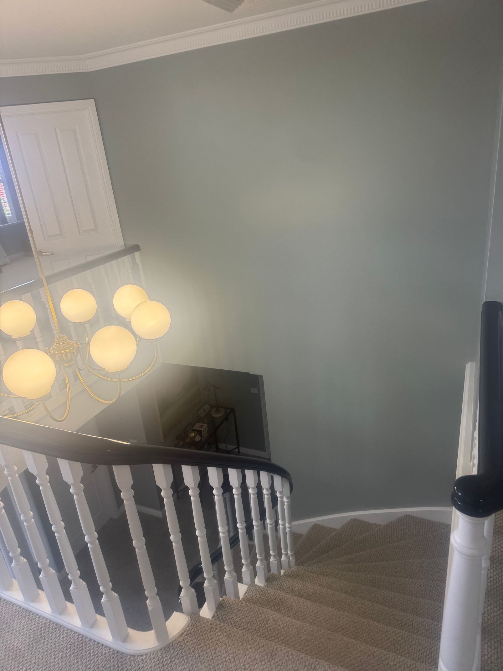 Stairwell with white railing, gray walls, carpeted floor, and hanging light fixture.