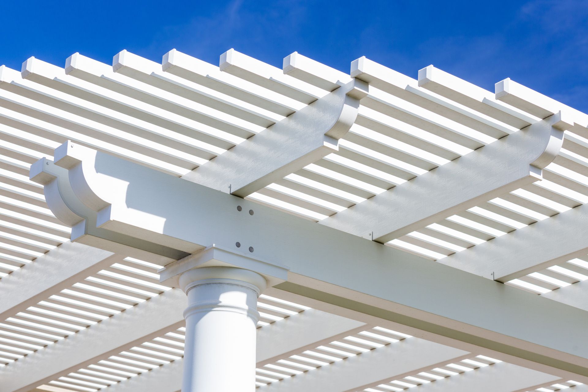 A white pergola with a blue sky in the background.