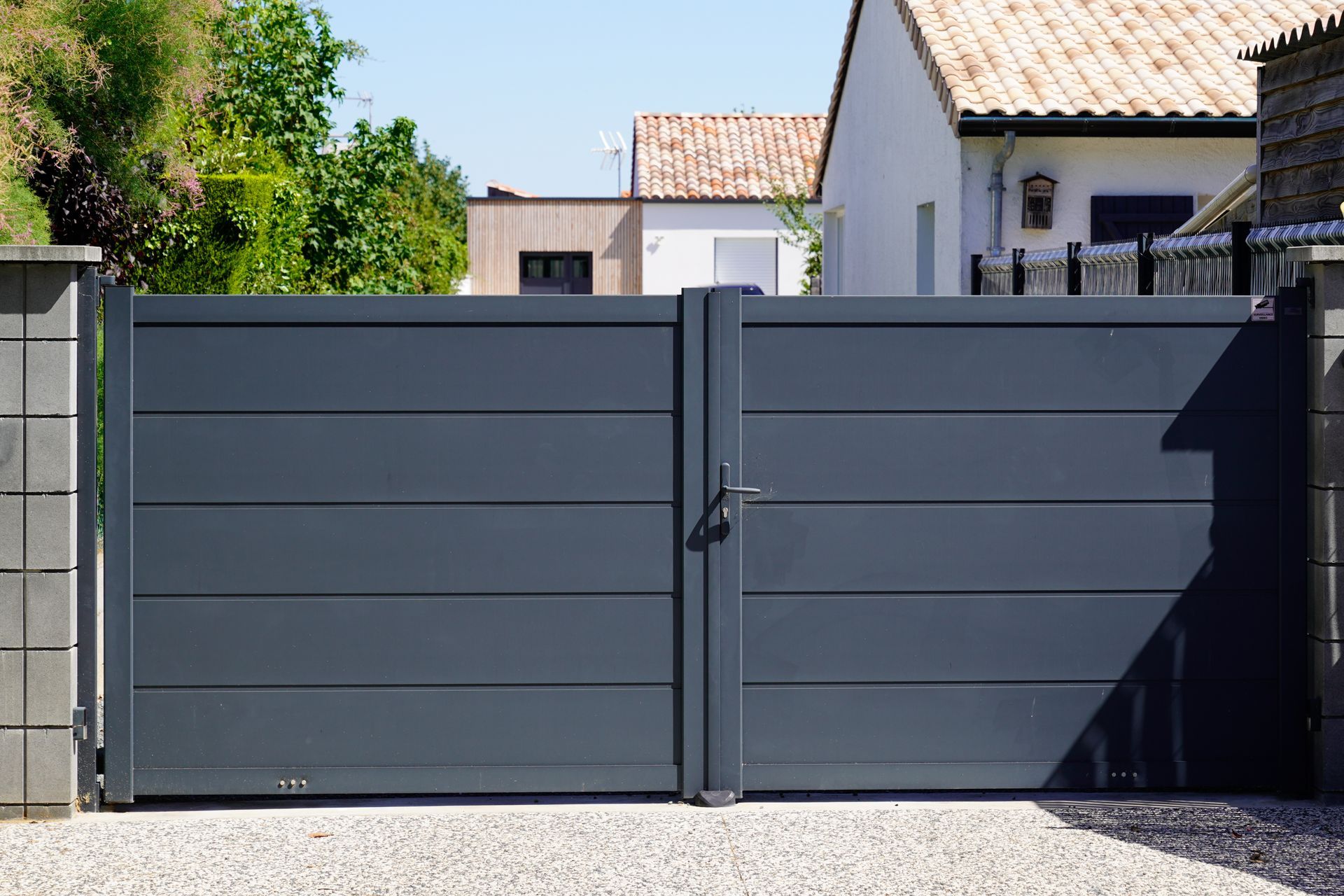 A gray gate is sitting in front of a house.