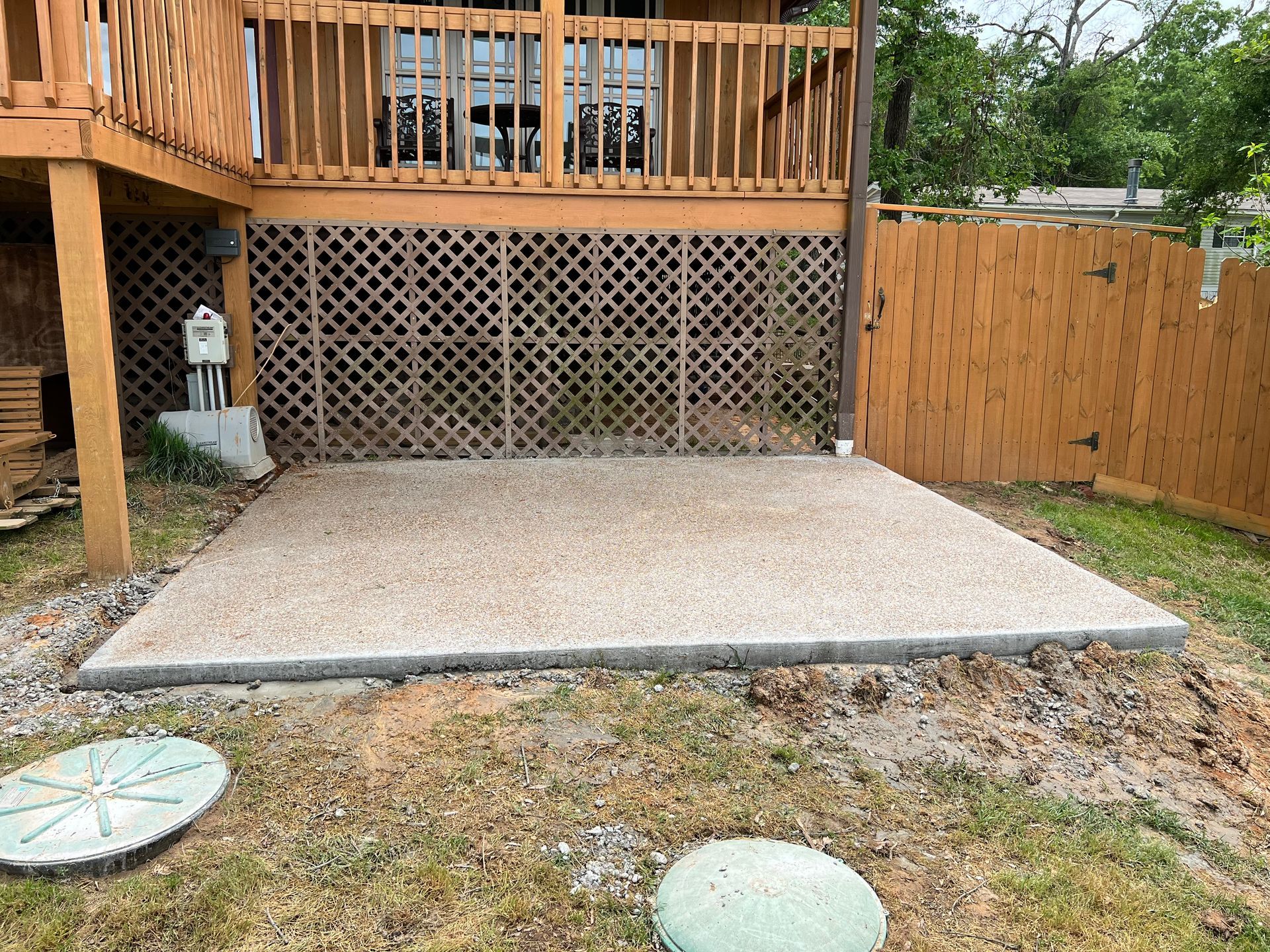 A concrete patio is being built in the backyard of a house.