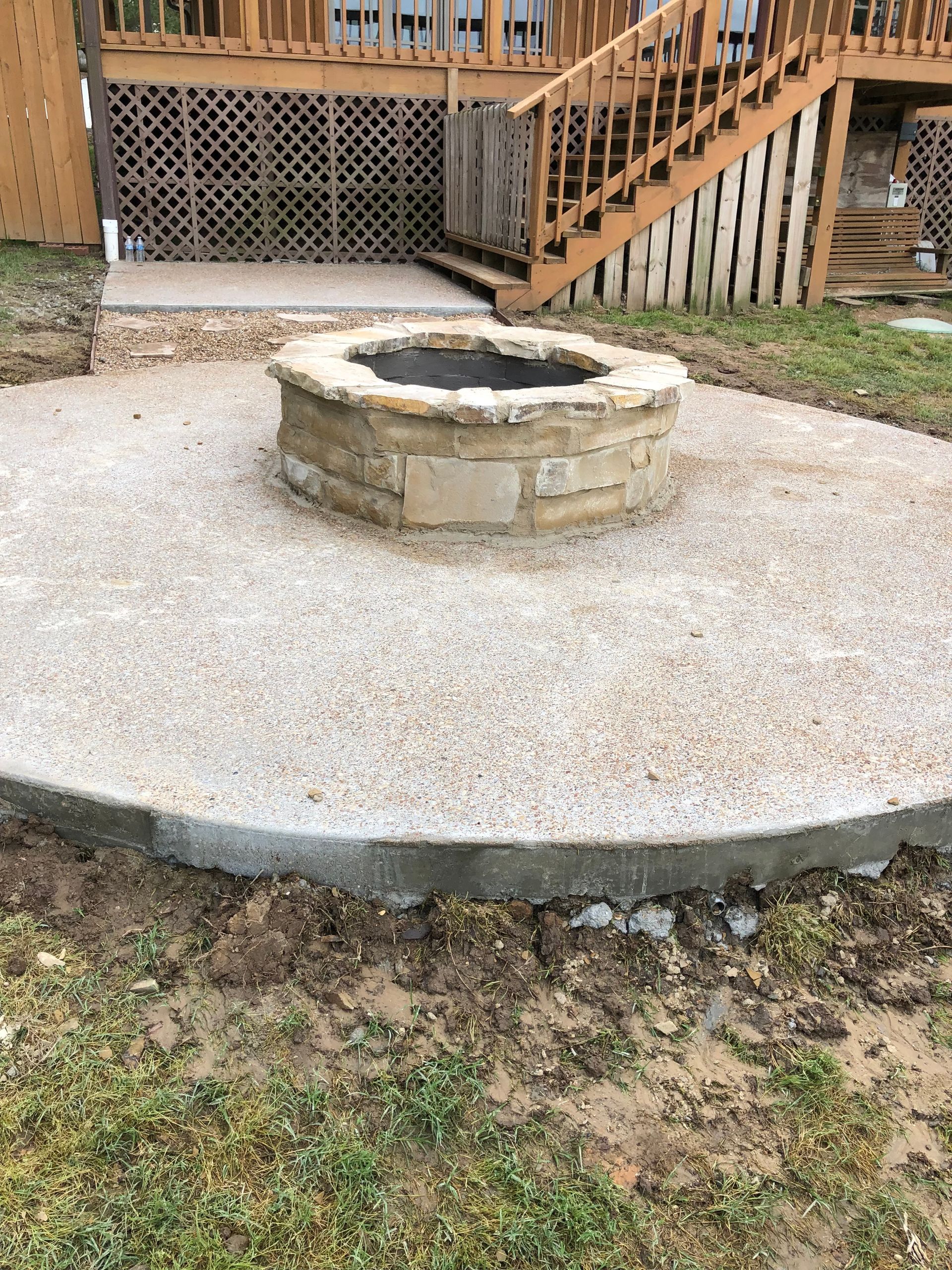 A fire pit is sitting in the middle of a concrete patio in front of a house.