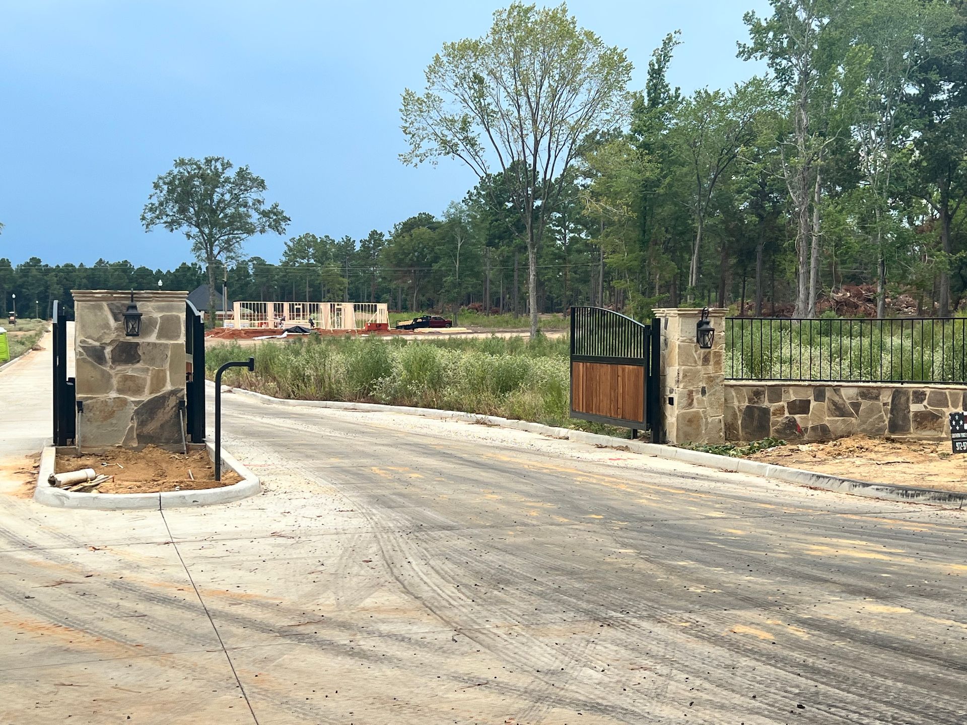A road with a stone wall and a wooden gate