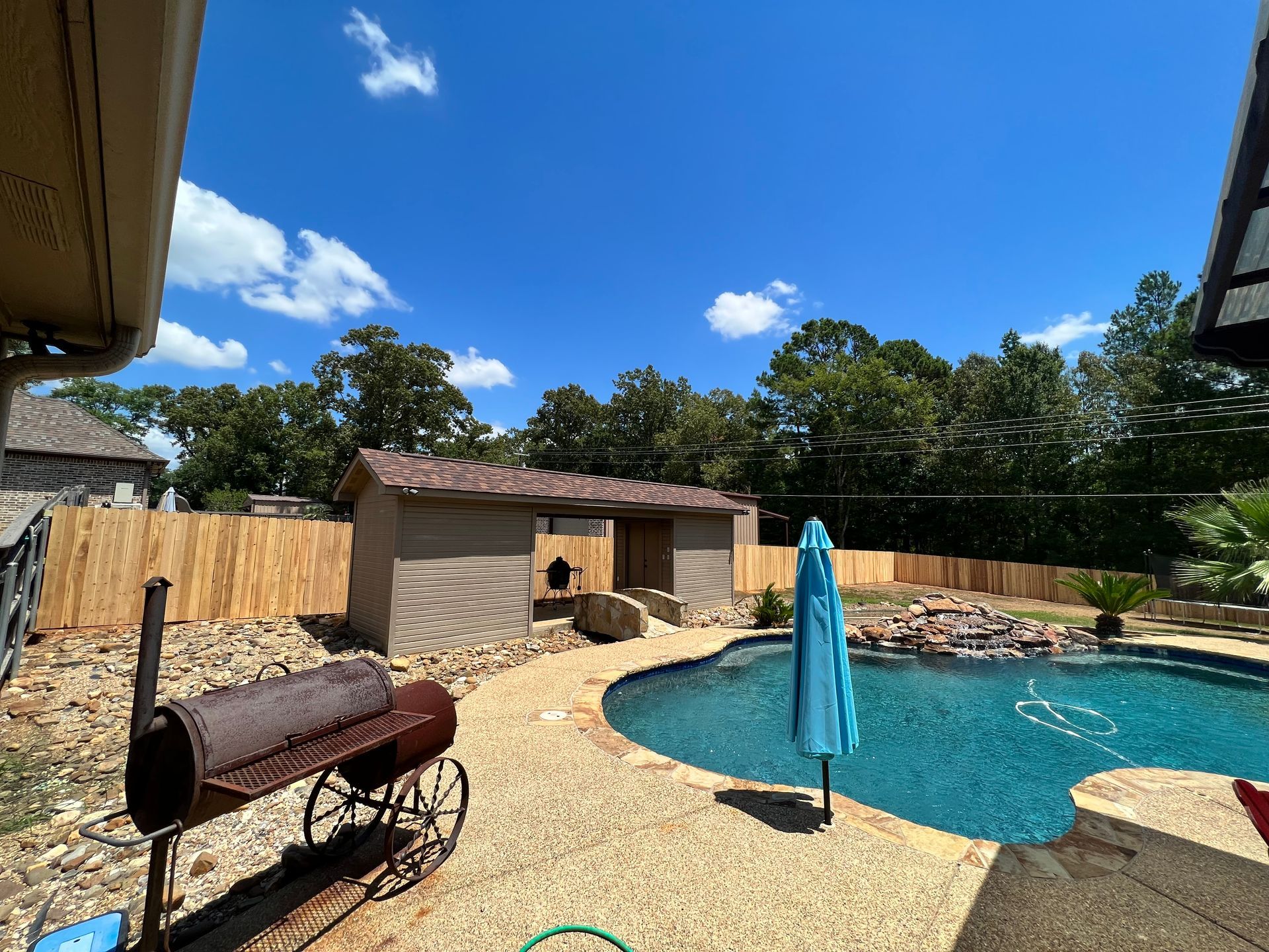There is a large swimming pool in the backyard of a house.
