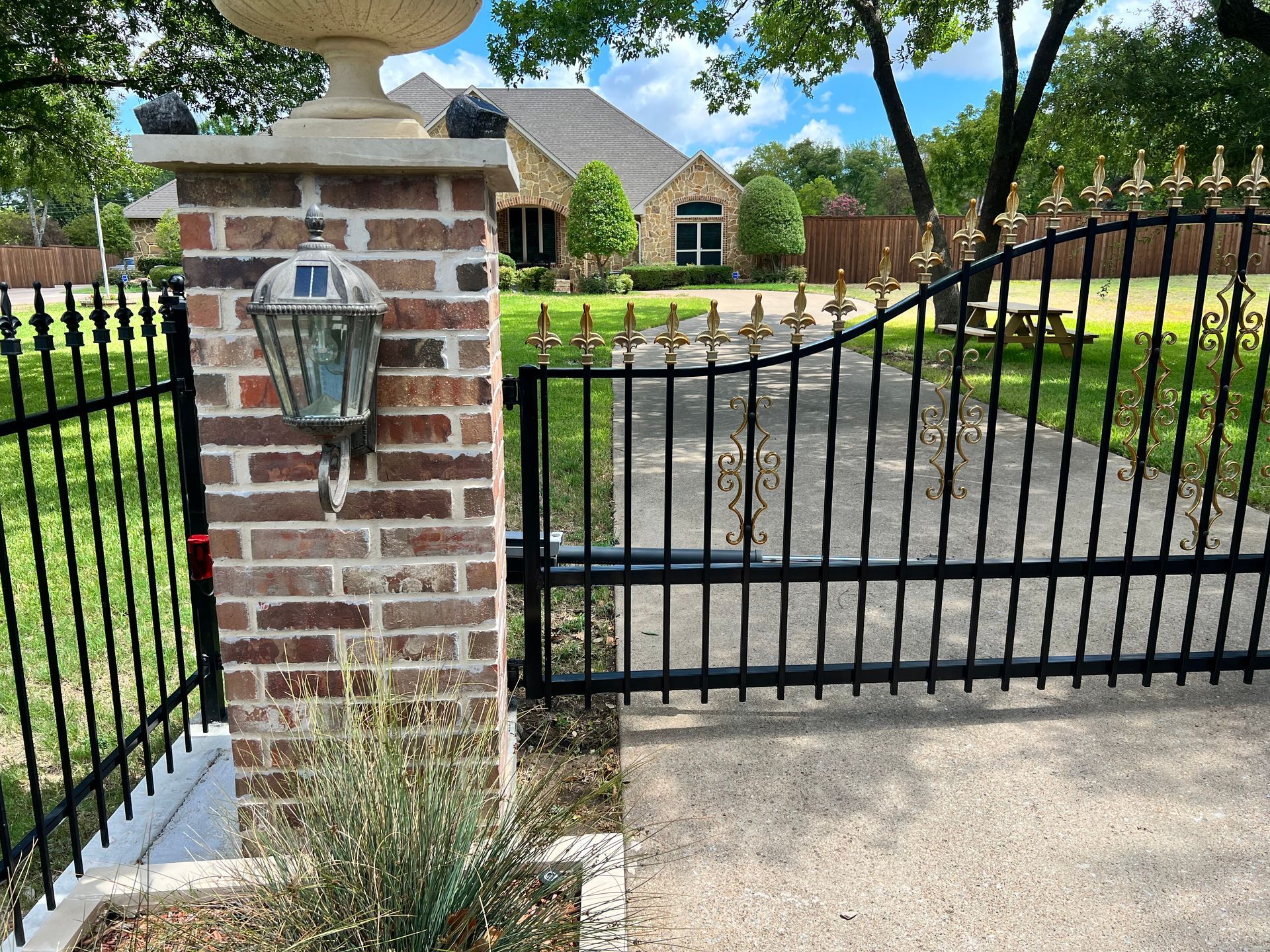 A black gate with a brick pillar in front of it
