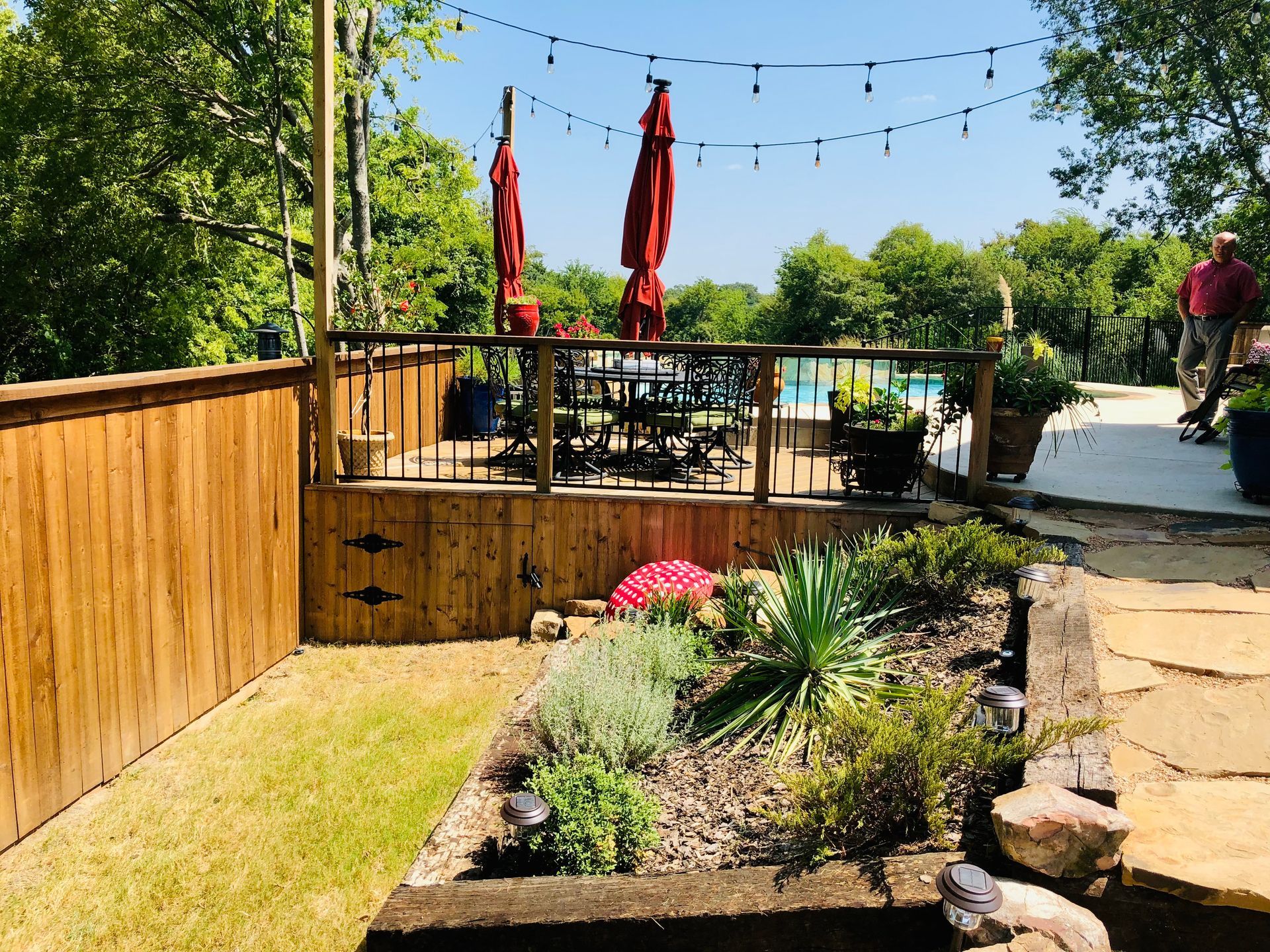 A backyard with a wooden fence and a swimming pool in the background.