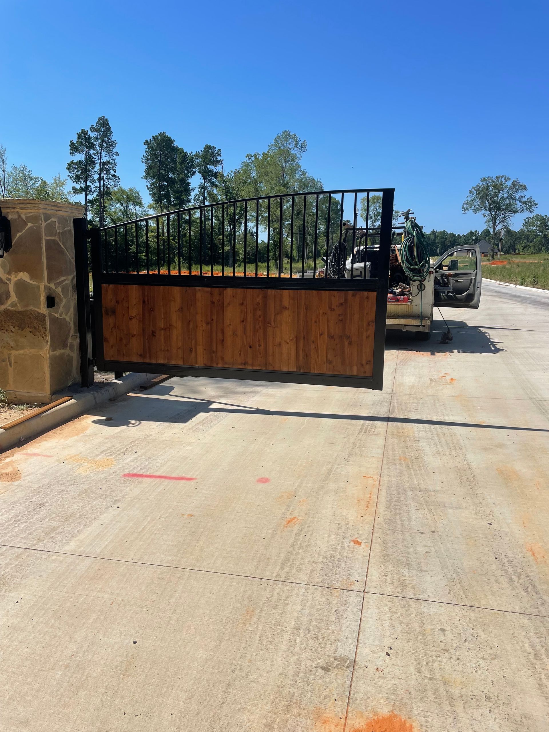 A wooden gate is open on a concrete road