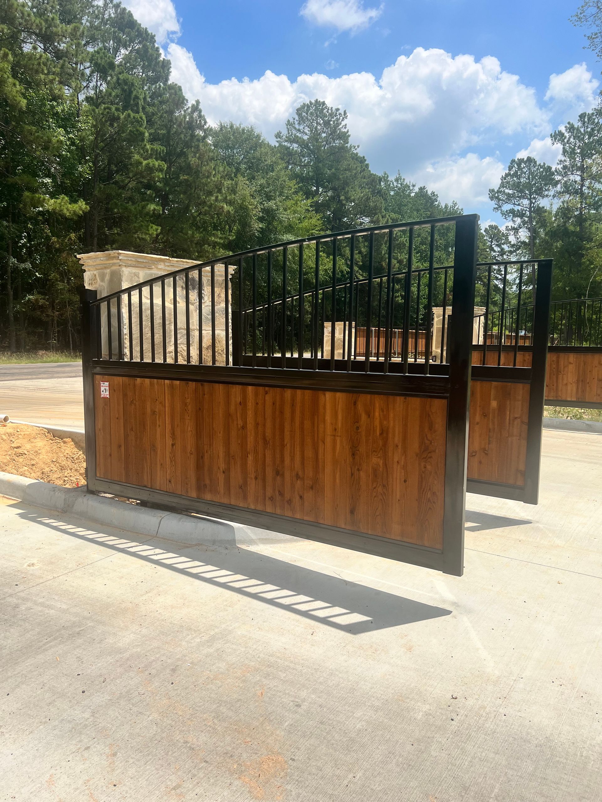 A wooden fence with a metal railing is sitting on the side of a road.
