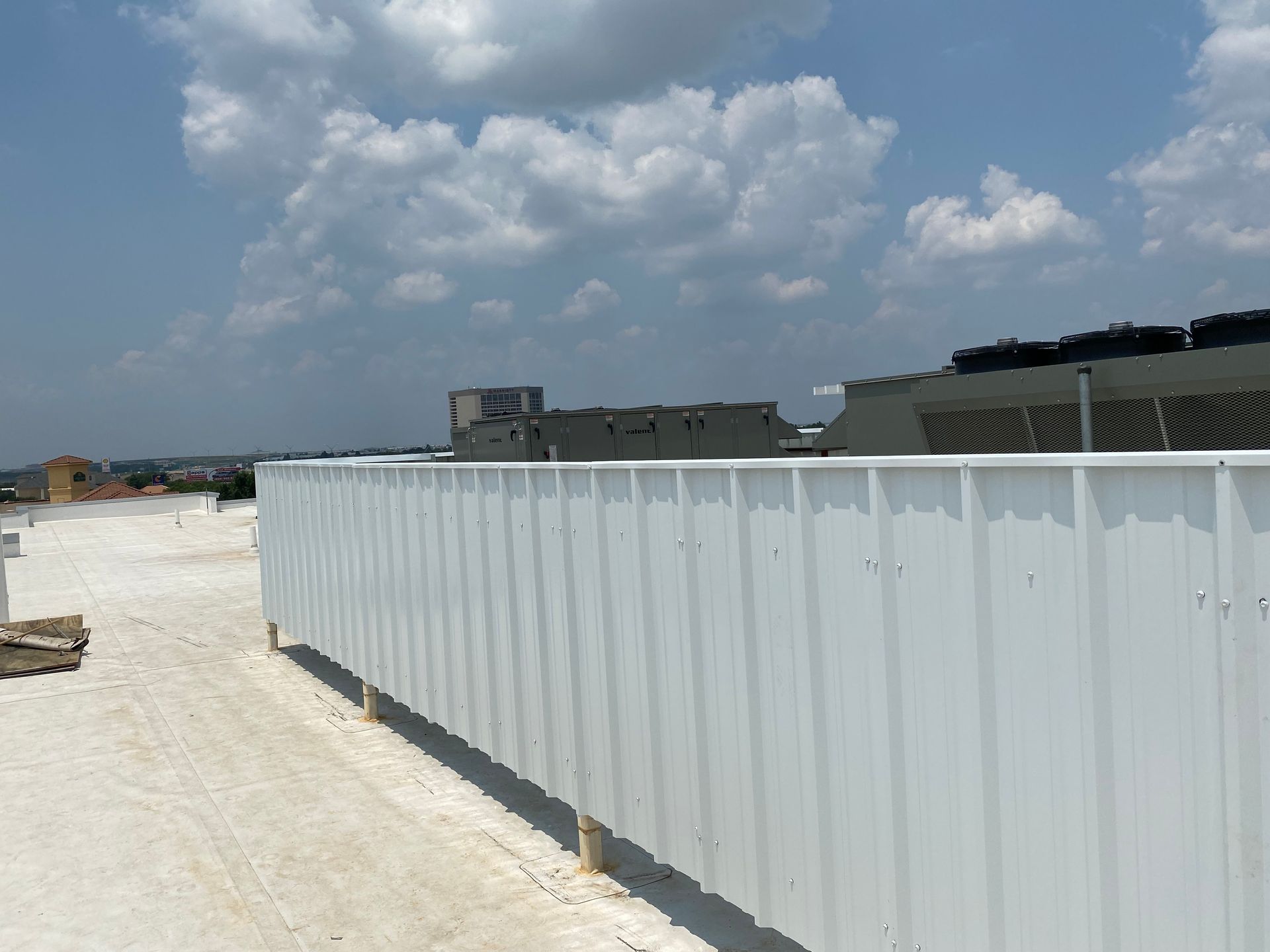 A white metal fence is surrounding a building under construction.