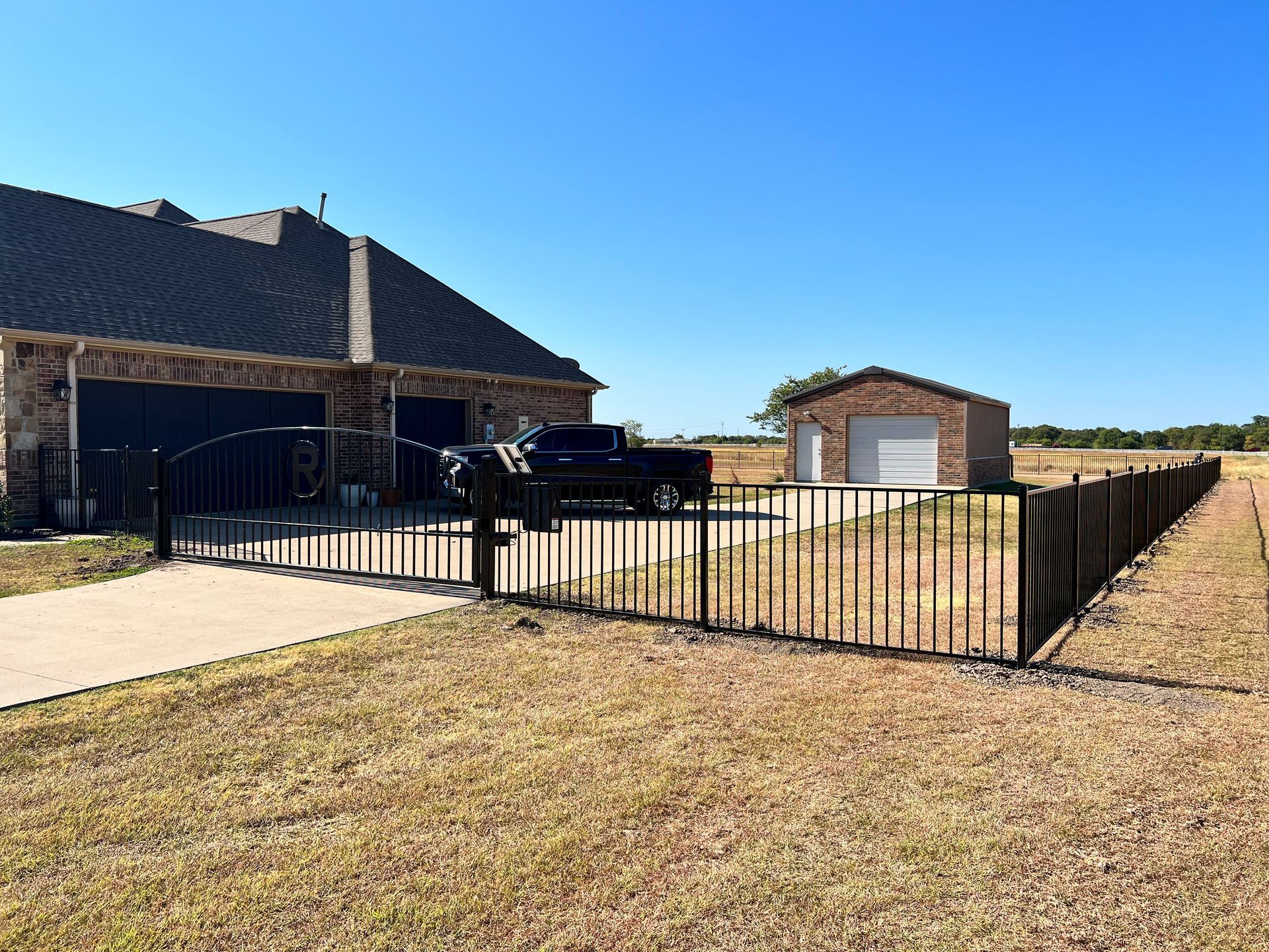 A house with a black fence and a truck parked in front of it.