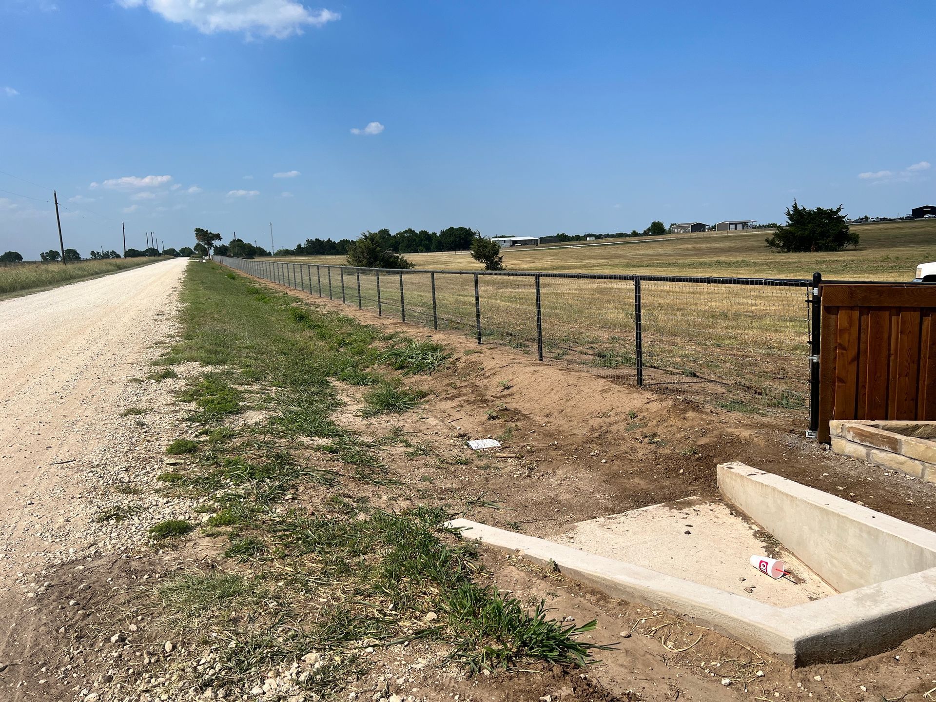 A dirt road with a fence along the side of it