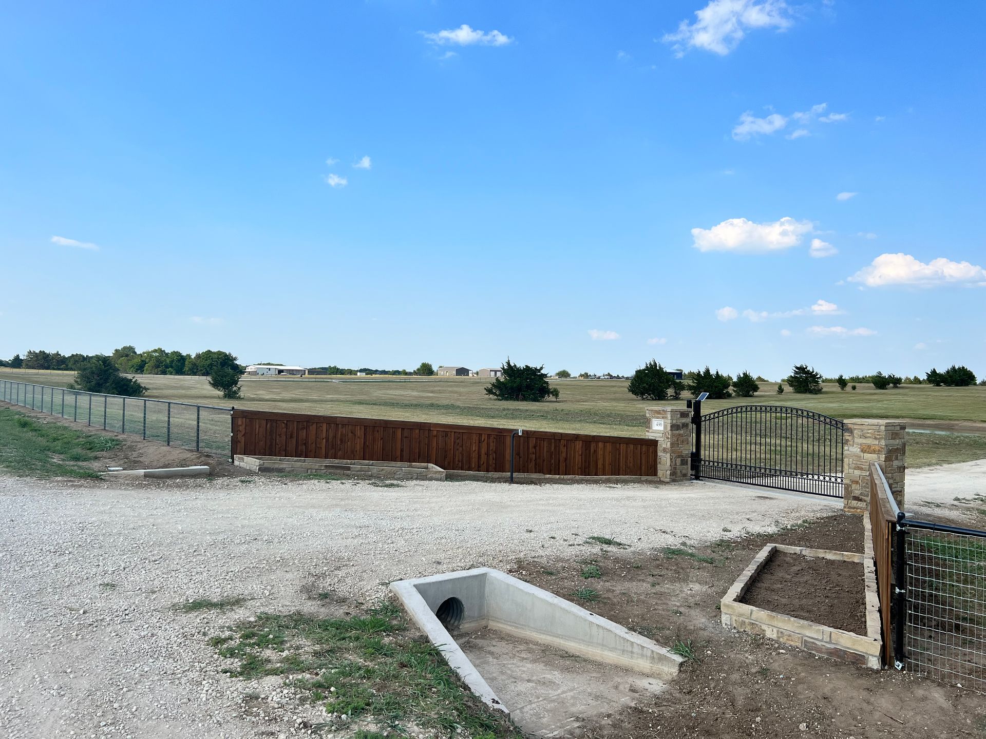 A gravel road with a wooden fence and a gate