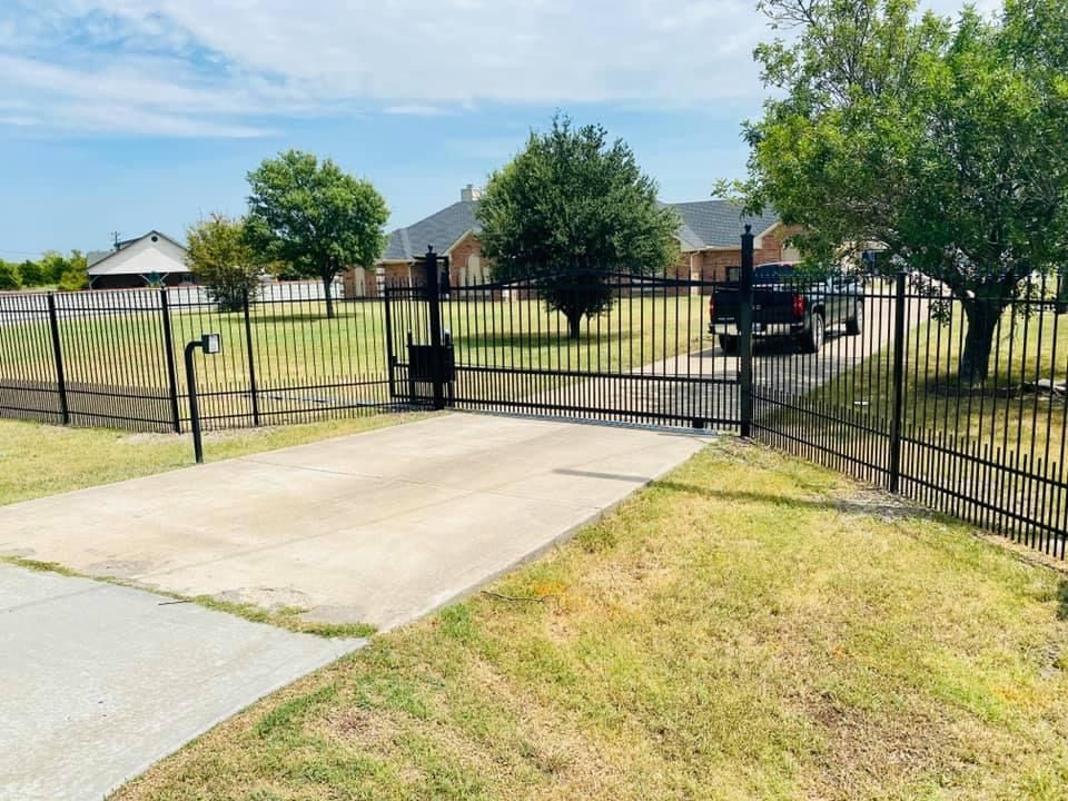 A driveway with a fence and a gate leading to a house.