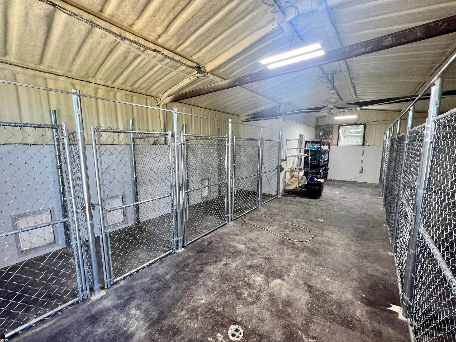 A room with a lot of chain link fences and a forklift in it.