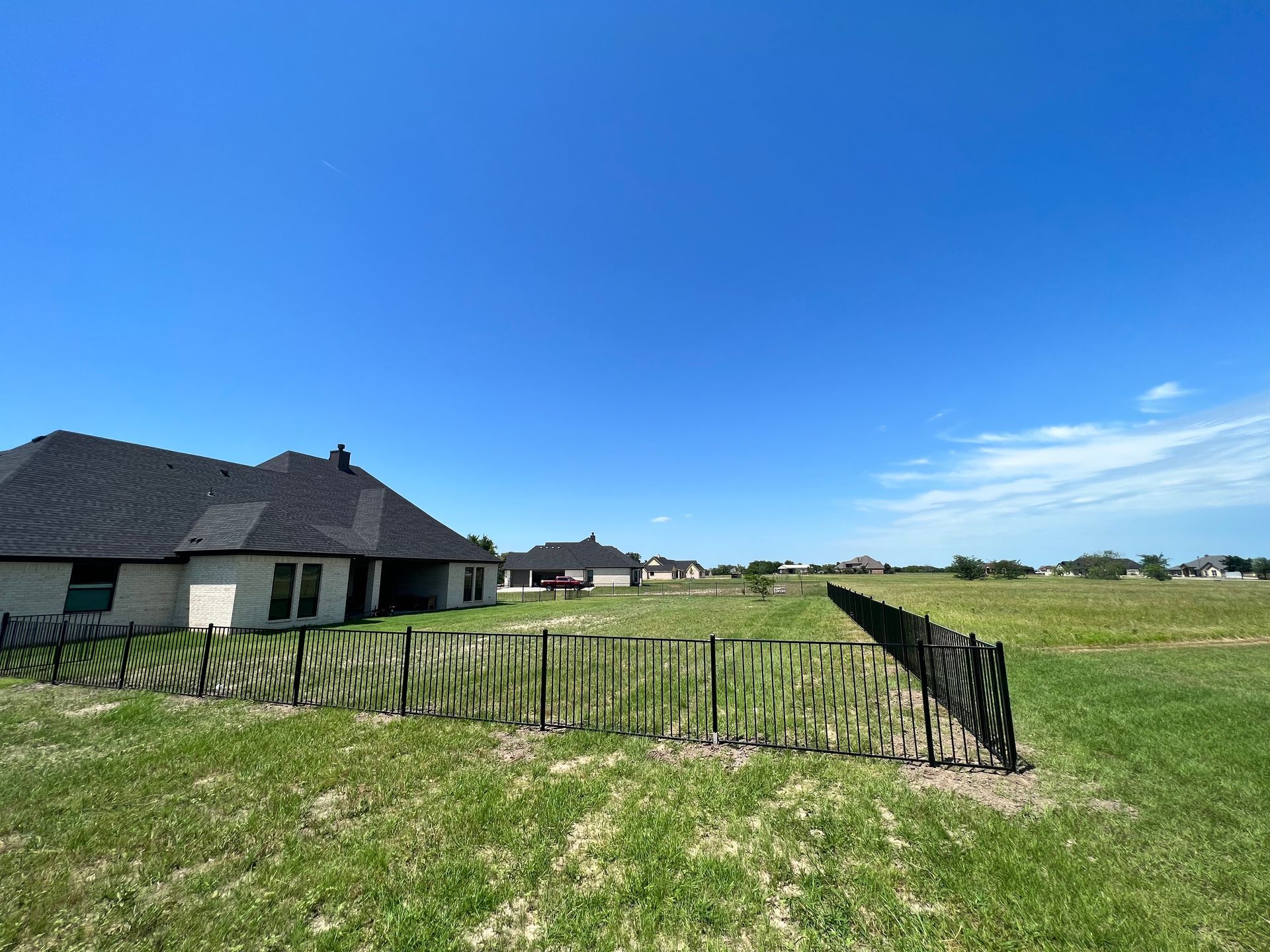 There is a house in the background and a fence in the foreground.