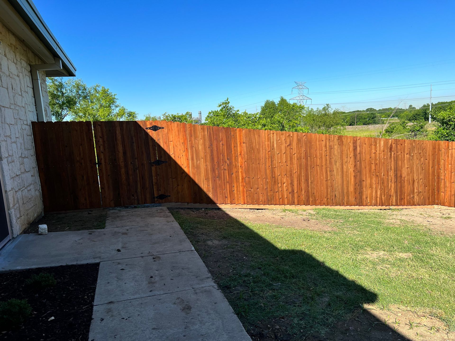 A wooden fence is in the backyard of a house.