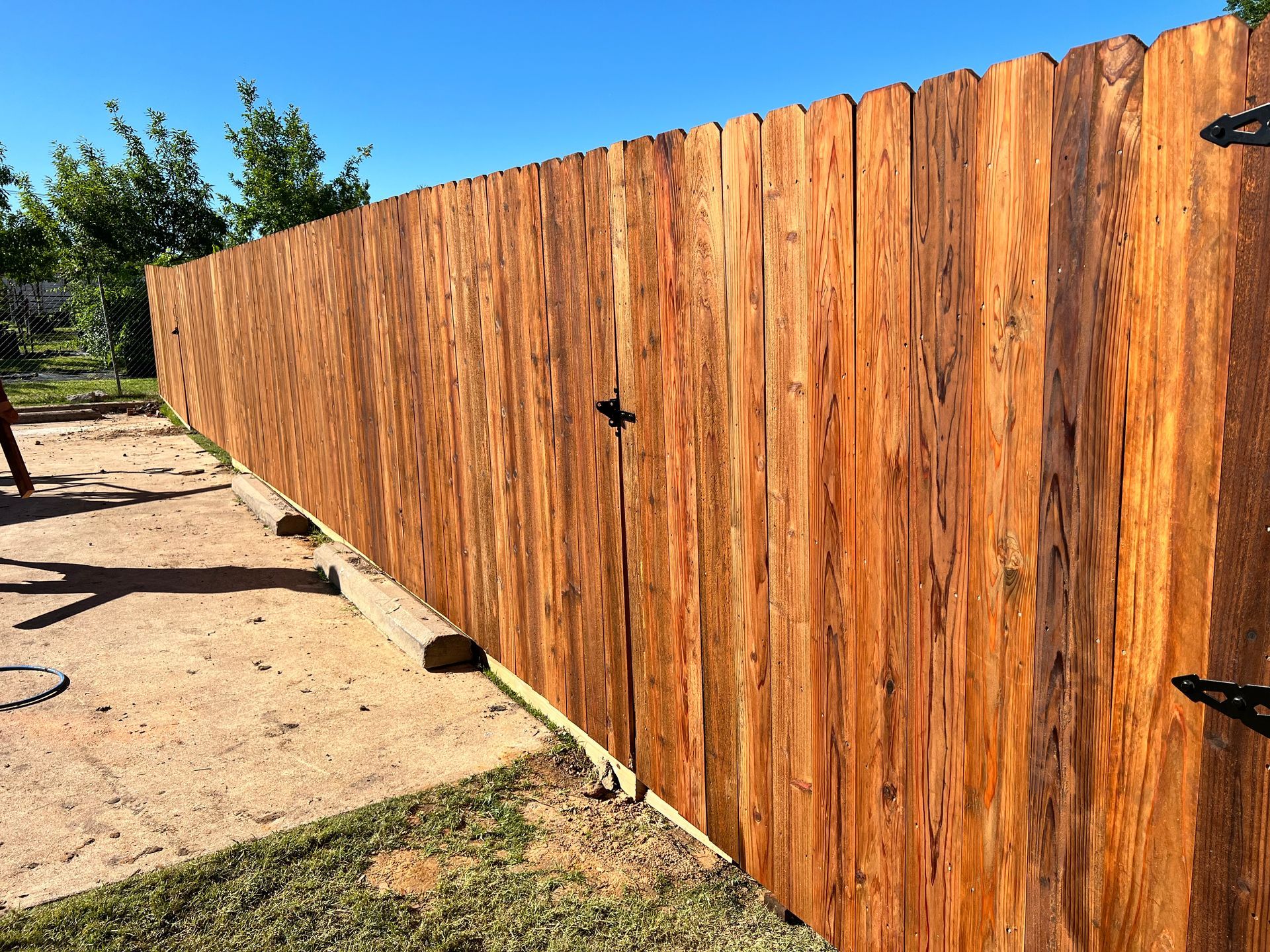 A wooden fence is being built in a backyard.