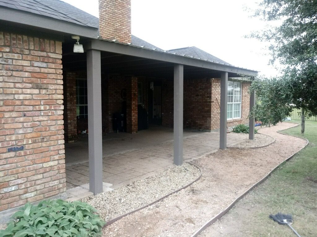 A brick house with a covered porch and a walkway leading to it.