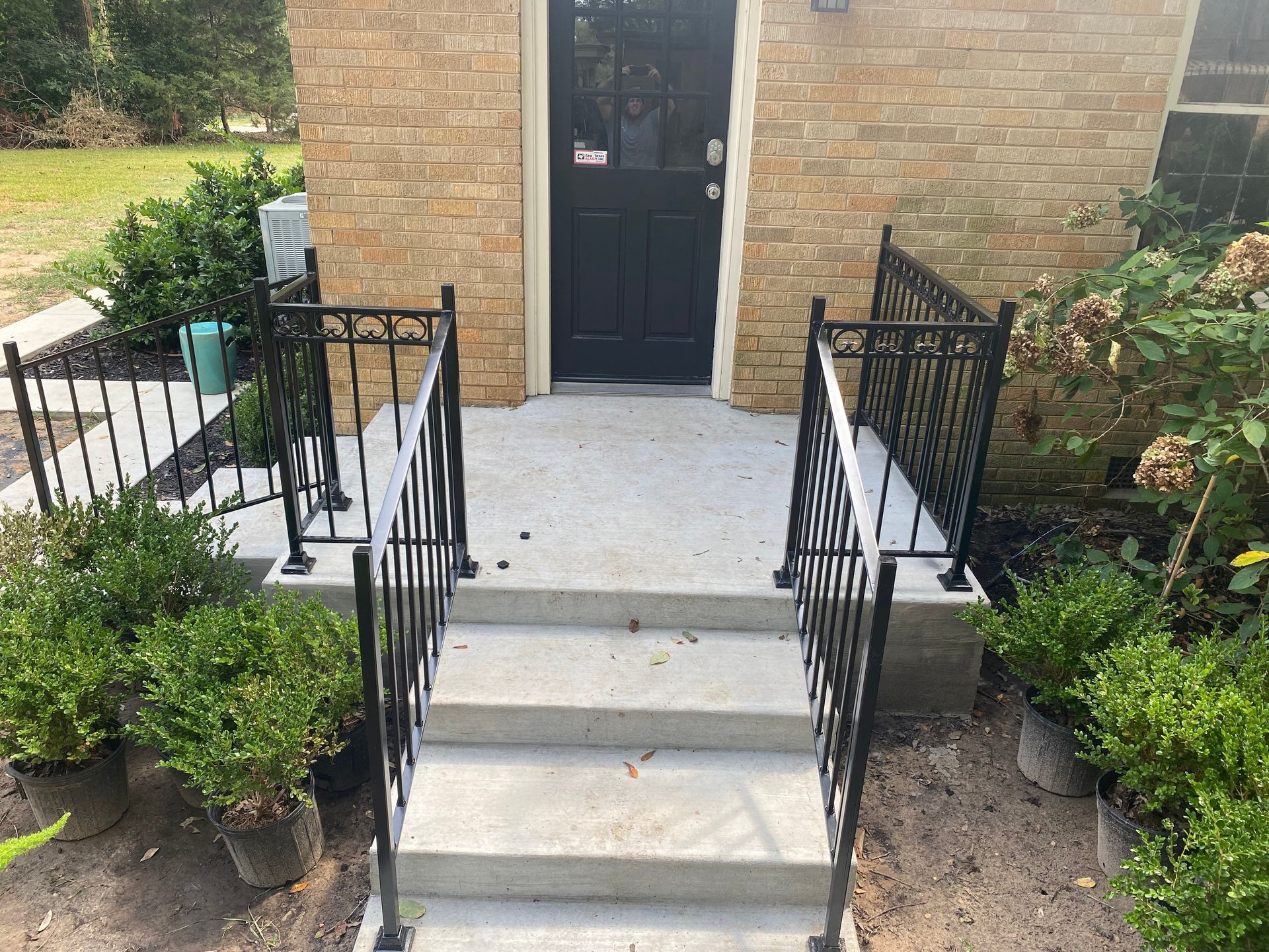 A brick house with a black door and stairs leading up to it.