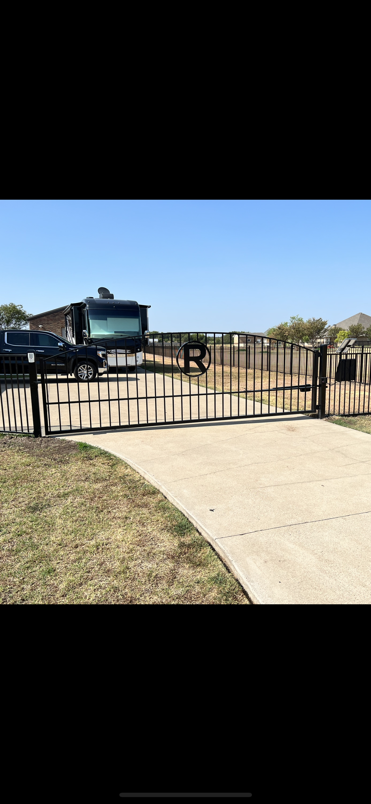A fence surrounds a dirt path leading to a house.