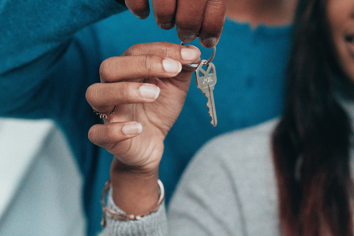 Person's hand holding house keys, giving them to another person.