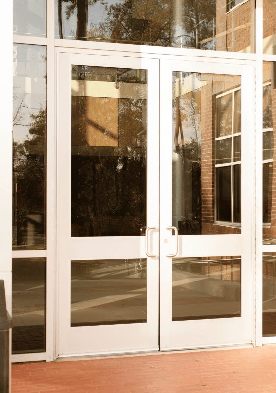 Double glass doors with white frames, leading into a building with brick exterior visible.
