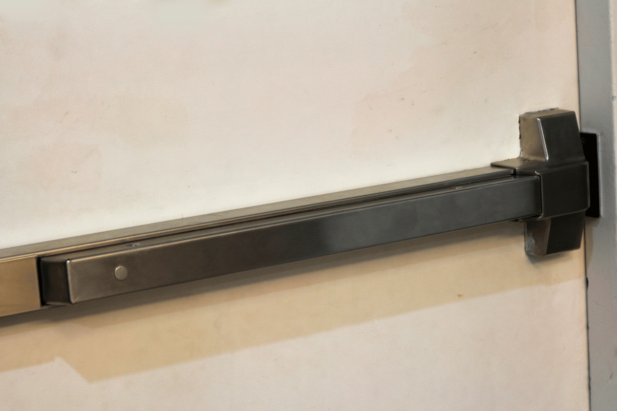 Silver exit bar on a white door, near a gray door frame.