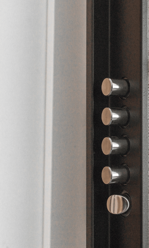 Close-up of a black door frame with four silver, protruding bolts and a knob.