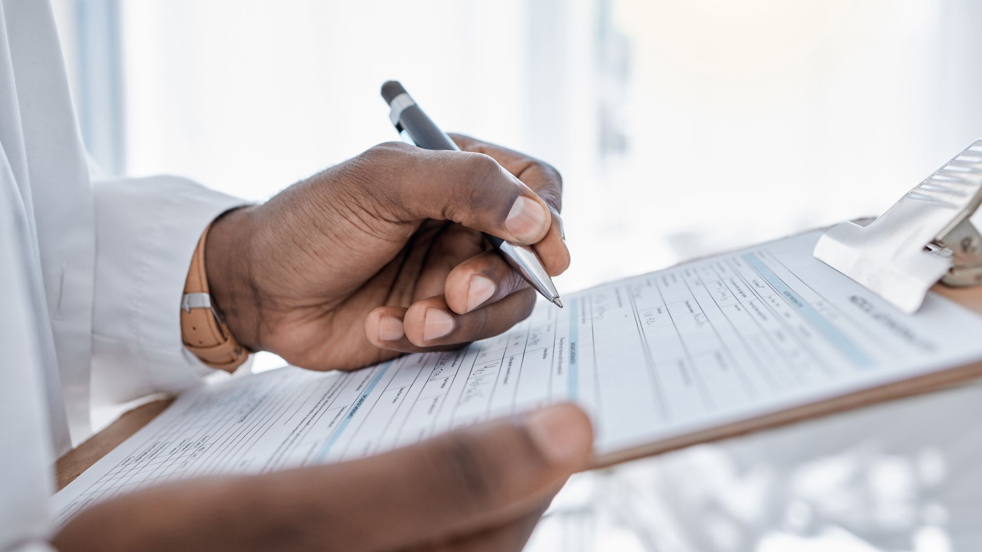 A person is writing on a clipboard with a pen.