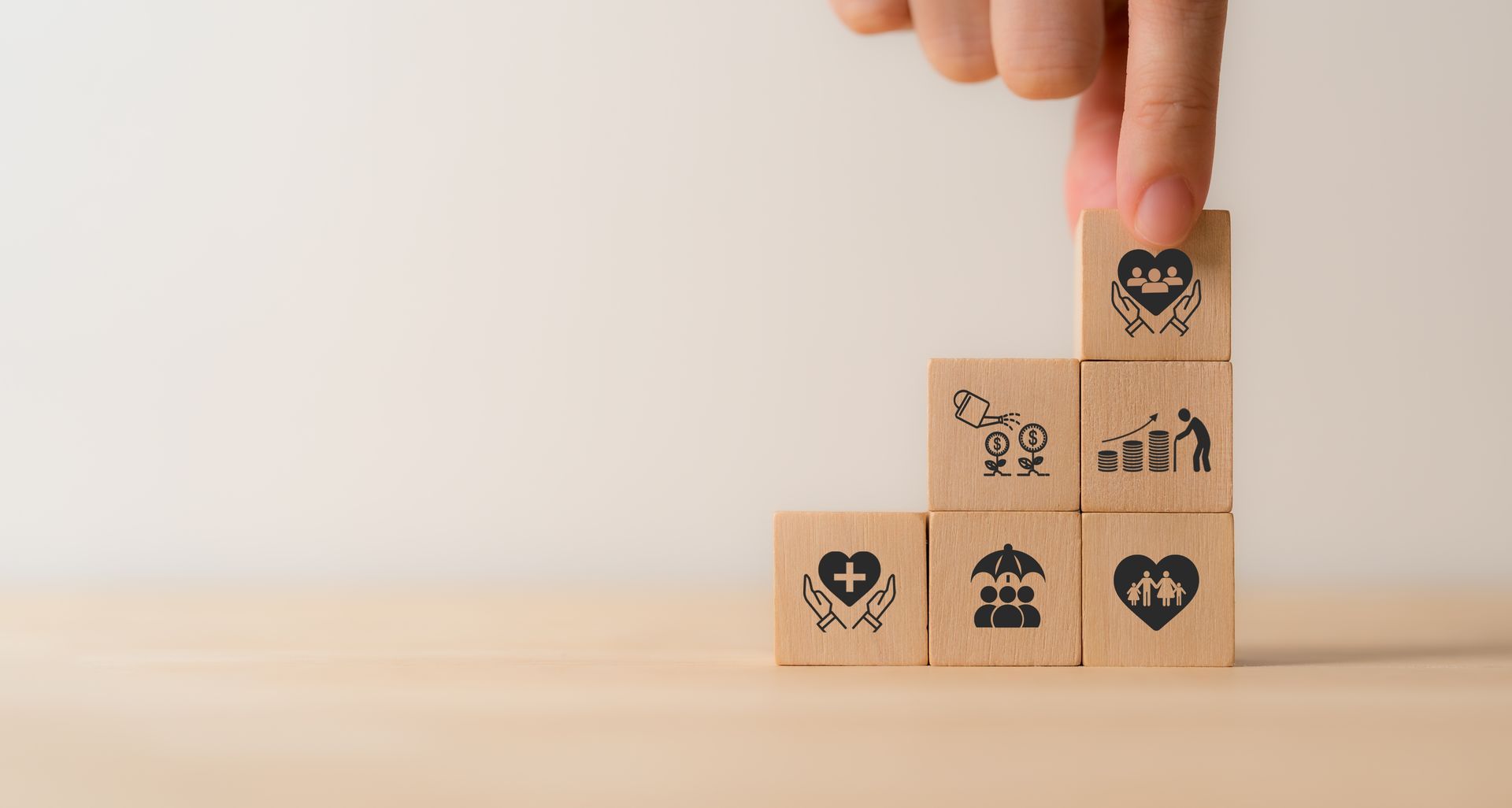 A person is stacking wooden blocks with icons on them.