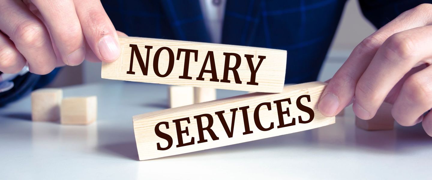 A person is holding wooden blocks with the words notary services written on them.