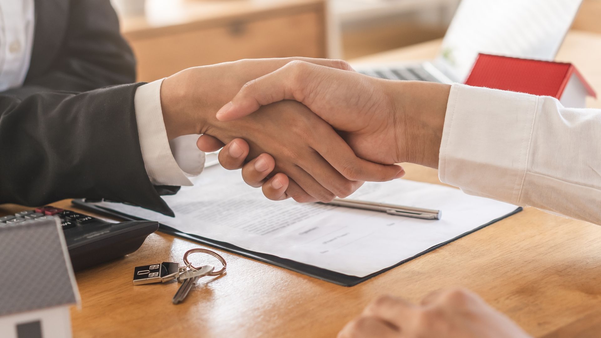 A man and a woman are shaking hands over a table.