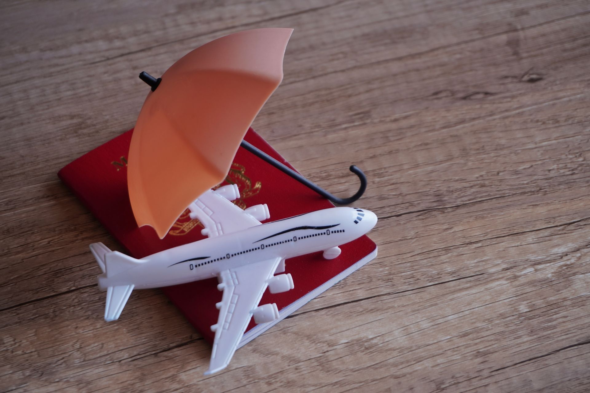 A toy airplane is sitting on top of a red passport.