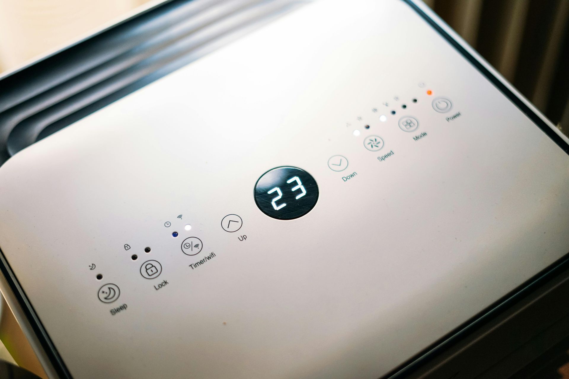 White air purifier control panel with digital display showing 23. Various buttons and indicator lights.