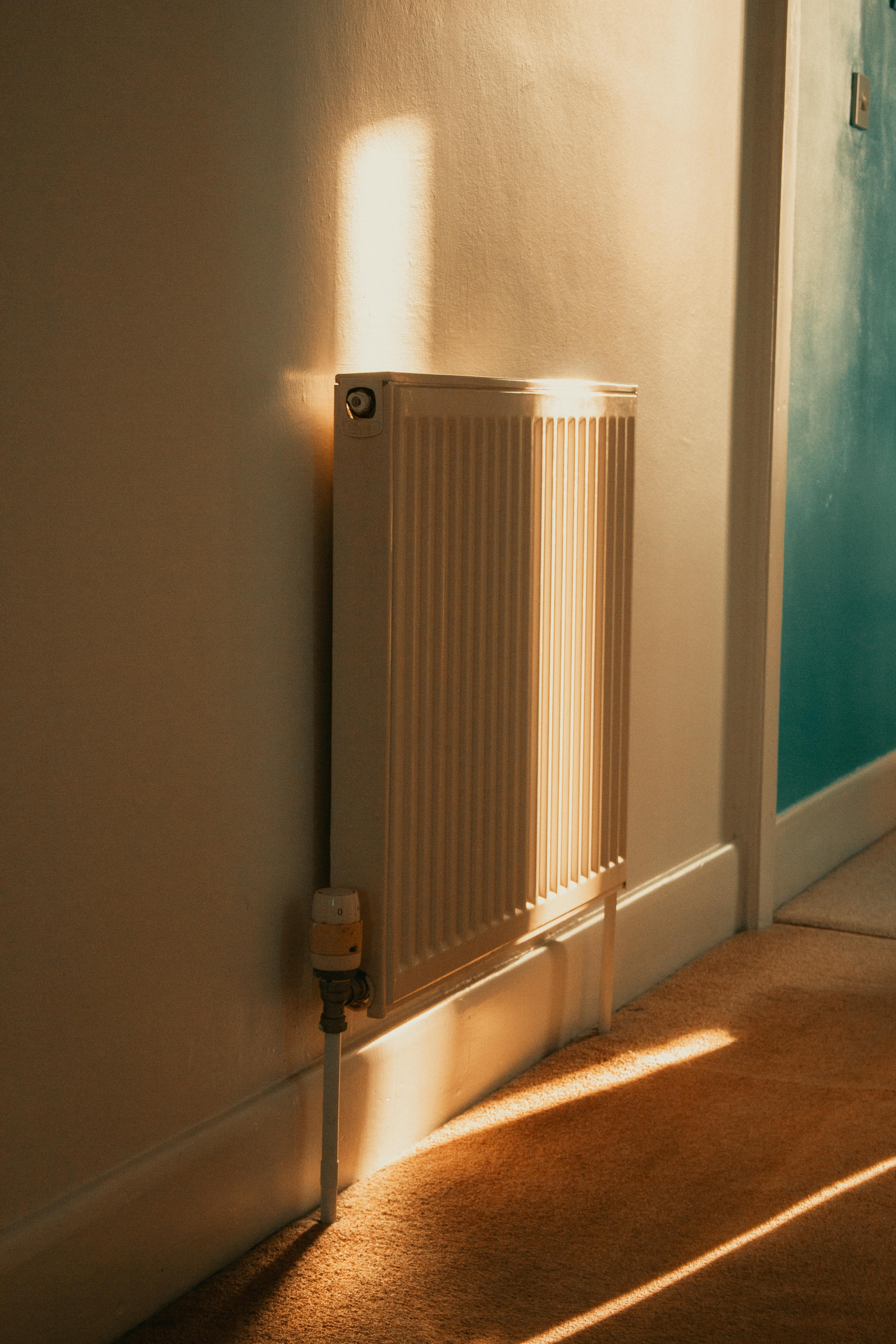 Sunlit hallway with a wall-mounted radiator casting long shadows on the floor