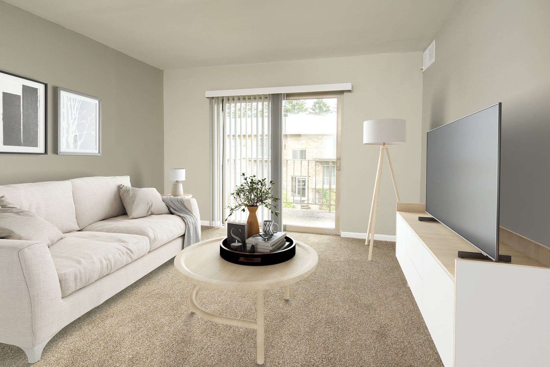 Living room with beige sofa, round coffee table, TV on a white console, and a sliding glass door at The Ridge Apartments in Hagerstown, MD