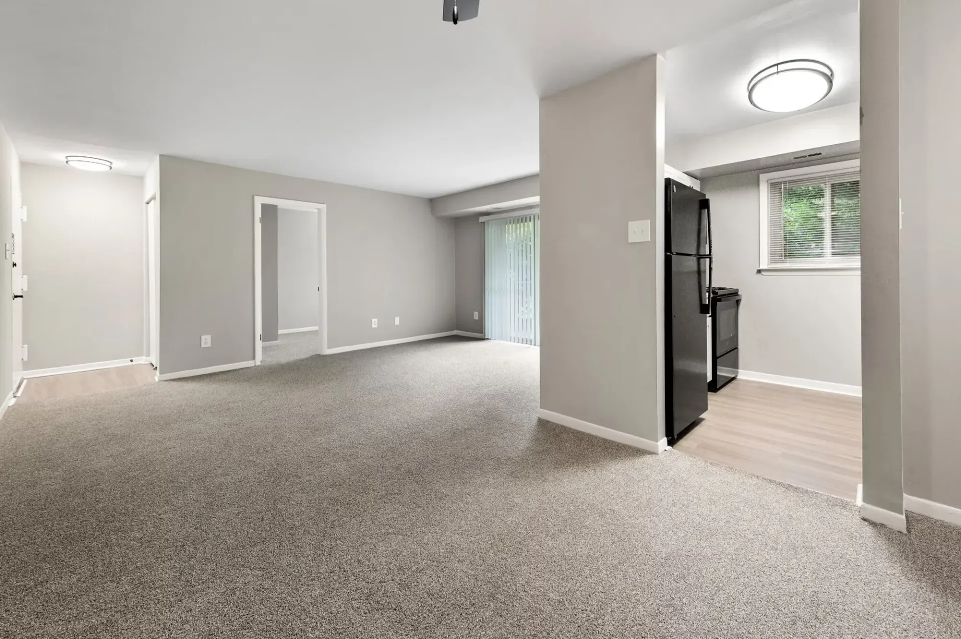 Open living area with gray walls, carpet, and a kitchen alcove visible to the right at The Ridge Apartments in Hagerstown, MD